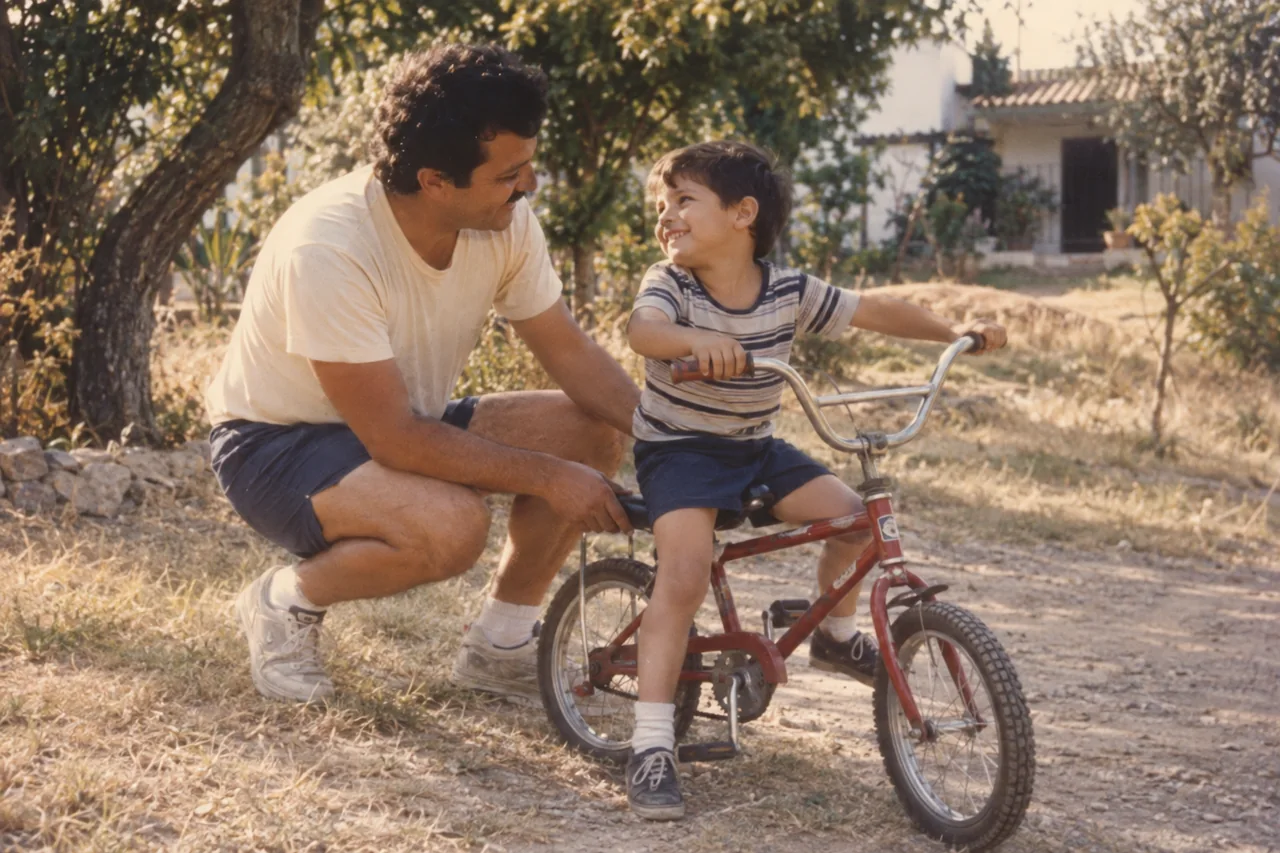 Un padre sostiene la bicicleta de su hijo mientras se sonríen.